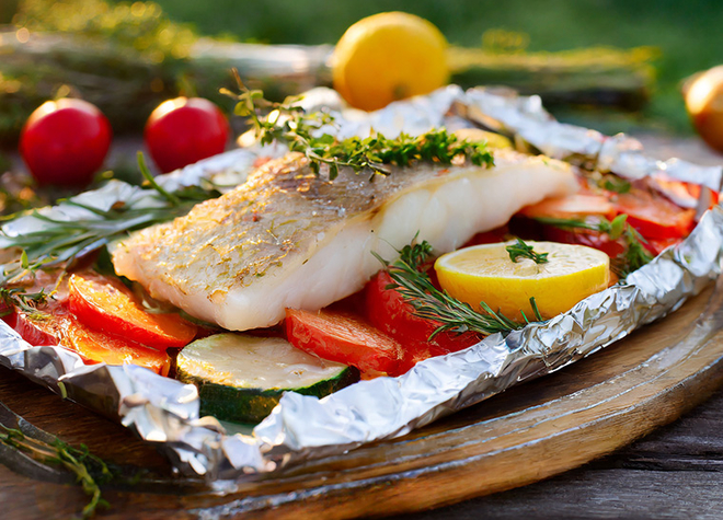 Zanderfilet auf Sommergemüse in der Folie auf dem Grill gegart