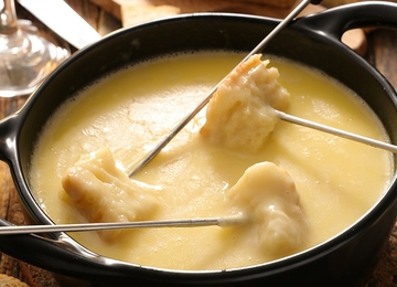 Käsefondue im Topf mit Gabeln, umgeben von Brot